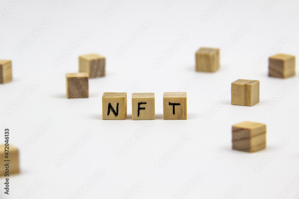 Word NFT (non fungible token) written on the wood cubes on white  background. Non-fungible tokens  concept NFT.