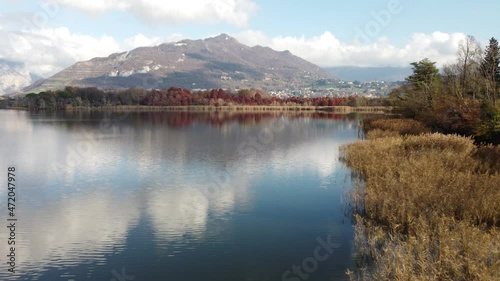 Aerial view of an alpine lake and the surrounding mountains and vegetations reflected on a cloudy day, Brianza, Lombardy, Italy