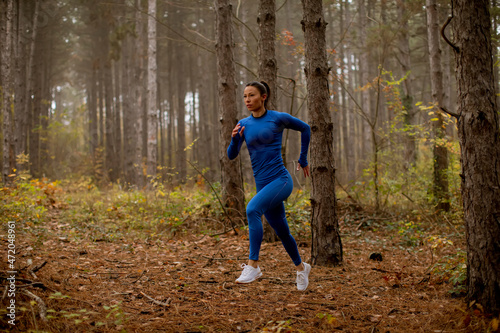 Young woman running on the forest trail at autumn