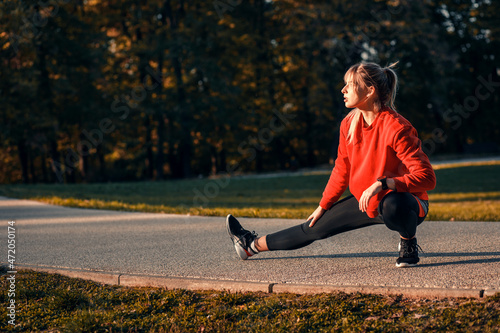 Young woman warming up and stretching before running in park.