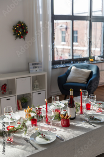 winter holidays, dinner party and celebration concept - christmas table serving with candles, crockery and wine at home