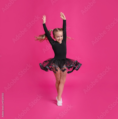 Stampa su tela Cute little girl in black dress dancing on pink background