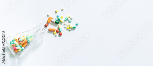 Pills and science experiments on white background, White medicine capsules spill out from transparent bottle,Prescription pill bottle spilling pills on to surface isolated on a white background.