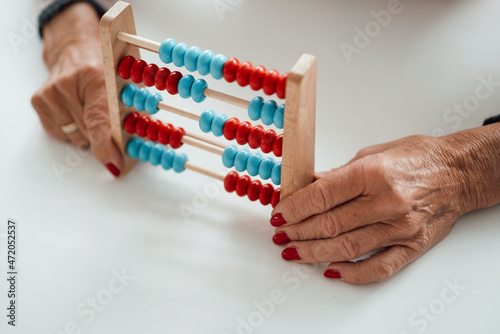 Senior woman holding abacus on table photo