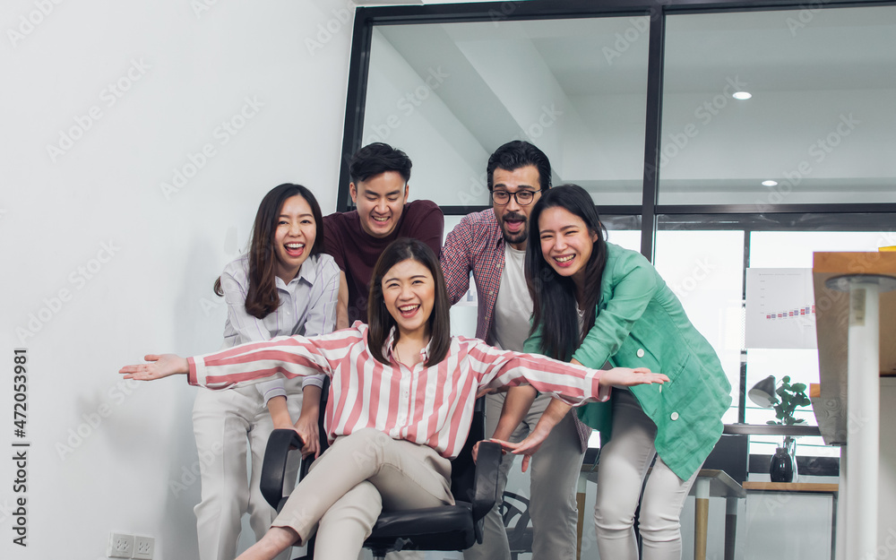 Group of teamwork businesspeople pushing a chair with female leader to move forward to achieve goal and success in modern indoor office. Business and Team concept.