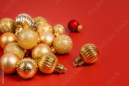 Red and gold Christmas balls lie on a red background, a beautiful minimalistic background for Christmas and New Year