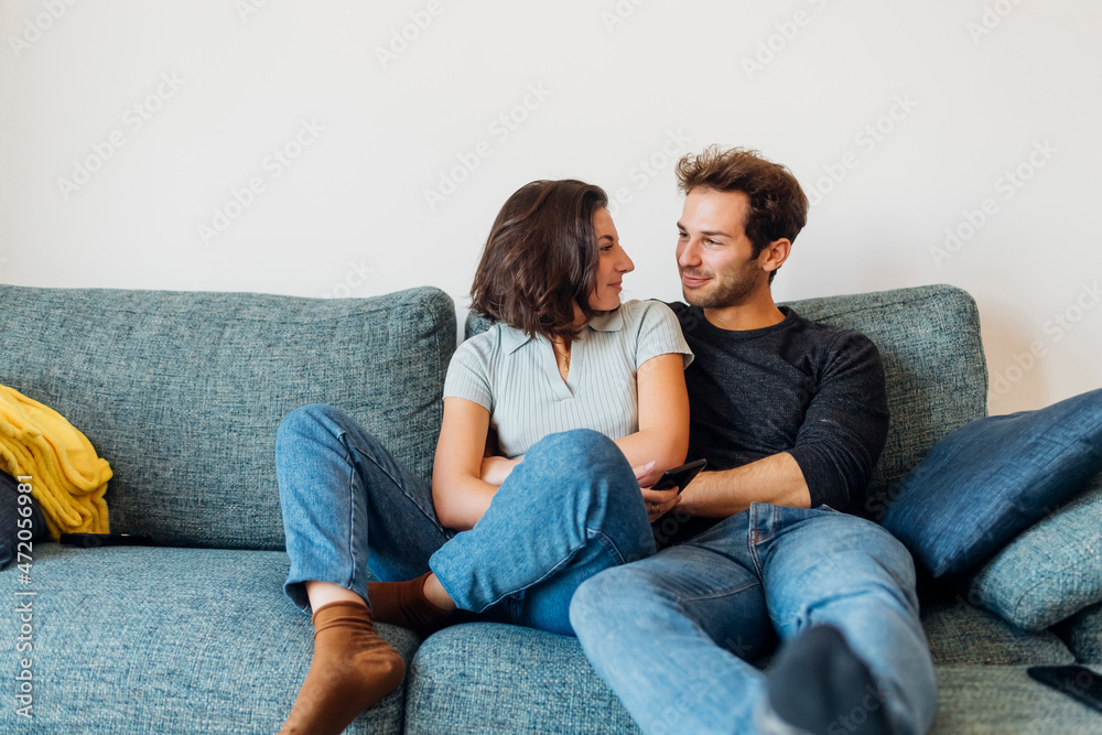 Smiling couple looking at each other while sitting on sofa Smiling couple looking at each other while sitting on sofa