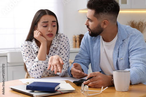 Young couple discussing family budget in kitchen