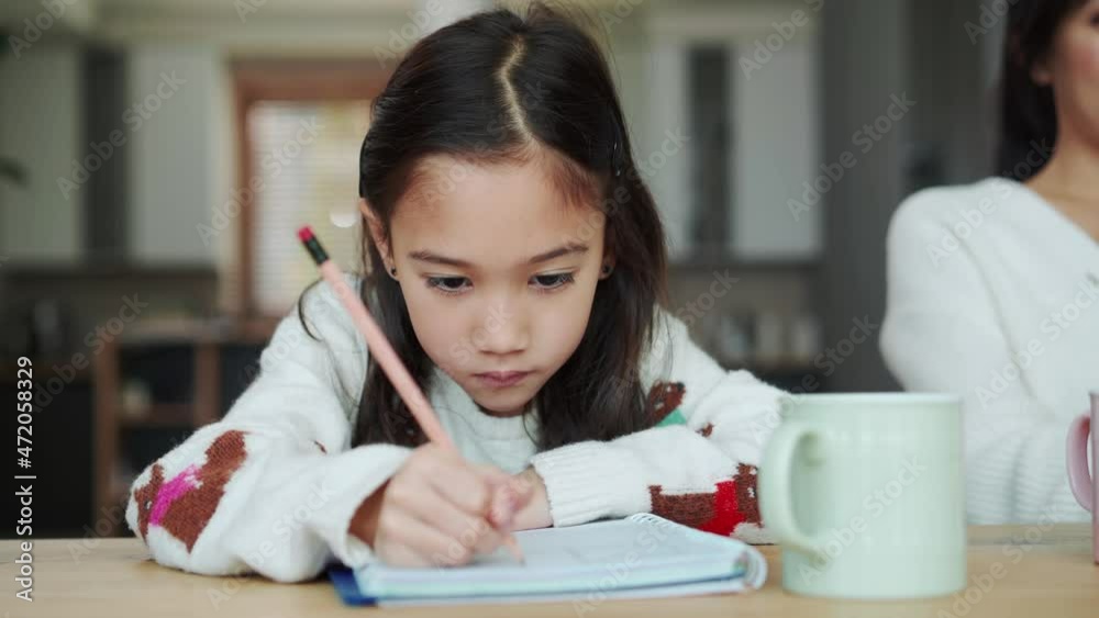 Confident Asian girl writing in notepad in the kitchen Confident Asian girl writing in notepad in the kitchen