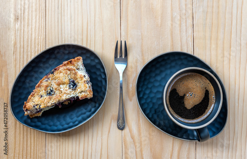 Homemade delicious sliced Apple Blueberry Pie on a black serving plate and a cup of black coffee on a wooden table. Top View