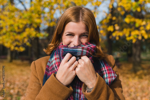 Happy woman covering mouth with stole in park photo