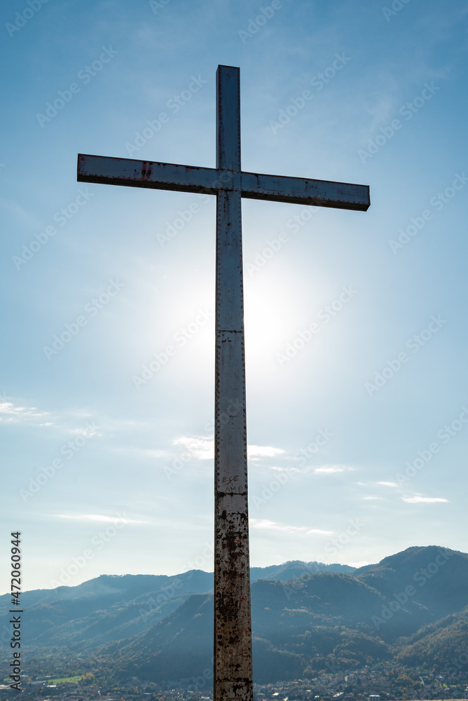 Silhouette of an iron cross at the summit of a hill where stands the Silhouette of an iron cross at the summit of a hill where stands the