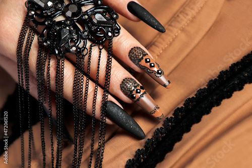 Nail design with black and beige nail polish with rhinestones.