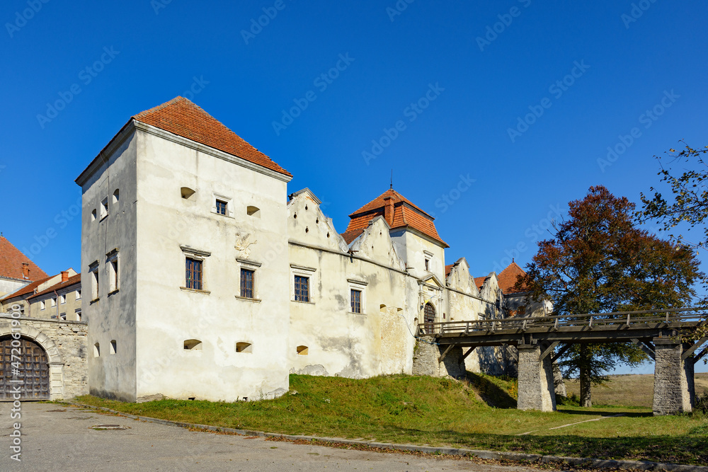 Autumn landscape with a view of the Svirzh castle, Ukraine. Sunny leaf fall day. An ancient fortification sits amid ponds and moats.