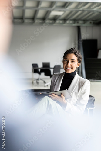 Smiling young businesswoman with tablet pc in meeting at office photo