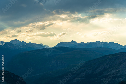 Golden hour and sunset with sunbeams through the clouds, as viewed while driving on the Going to the Sun Road in Glacier National Park in Montana on a beautiful sunny summer evening