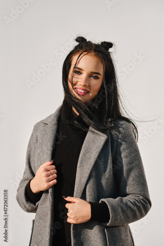 Young woman posing in warm coat with white wall on background