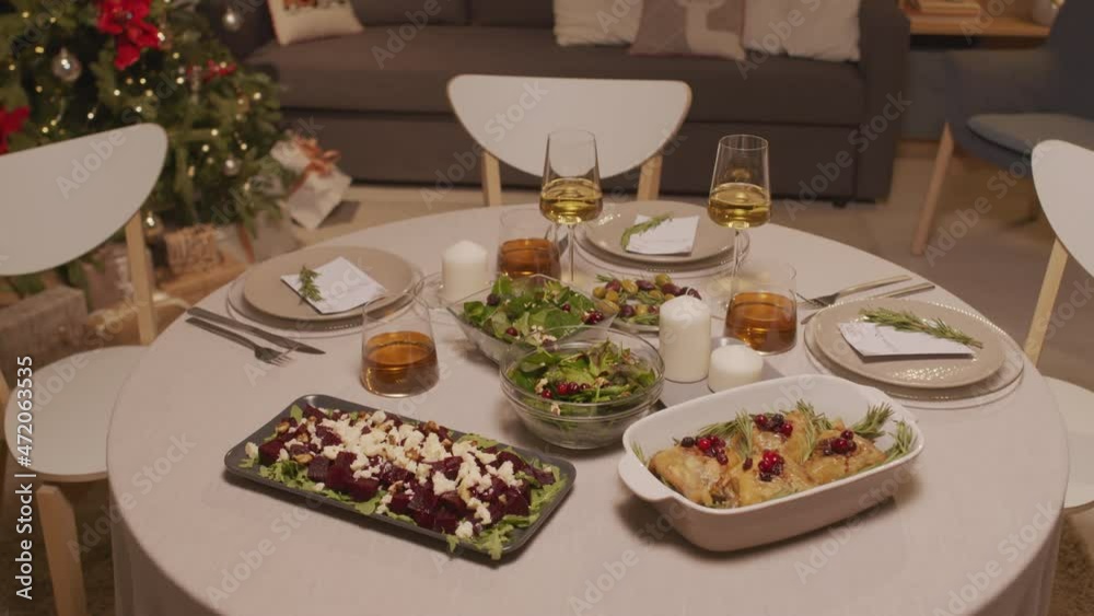 Handheld tracking of tasty dishes and glasses of wine on dinner table in living room with lit Christmas tree Handheld tracking of tasty dishes and glasses of wine on dinner table in living room with lit Christmas tree
