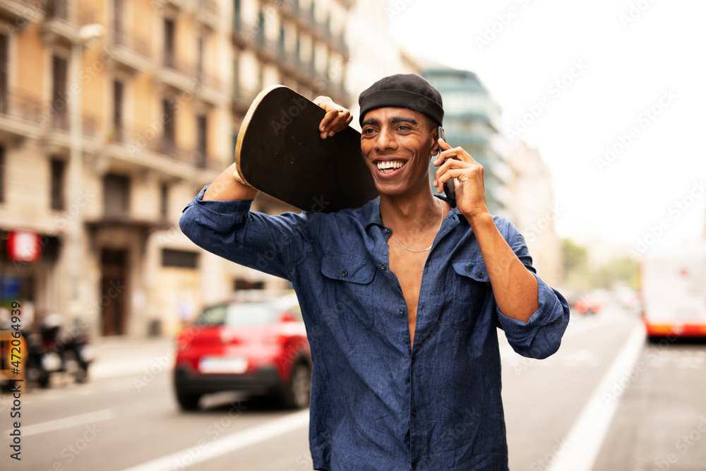African man with skateboard. Young handsome man using the phone. African man with skateboard. Young handsome man using the phone.