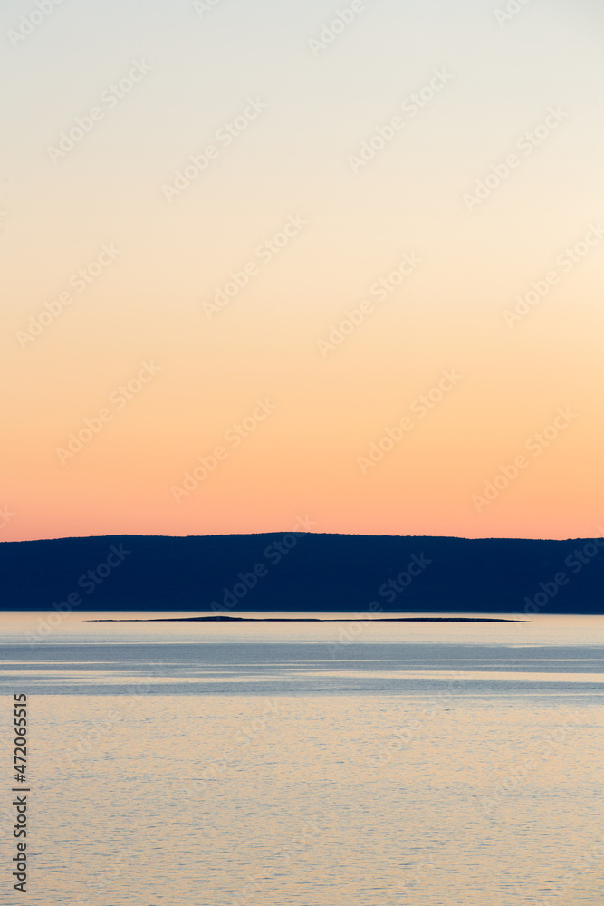 Sunset over the sea and landscape with blue sky and almost no clouds