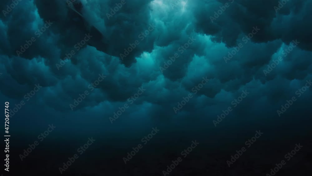 Ocean wave forms underwater clouds. Crystal clear ocean wave rolls and breaks. Underwater view of the powerful ocean wave breaking and creating bubbles