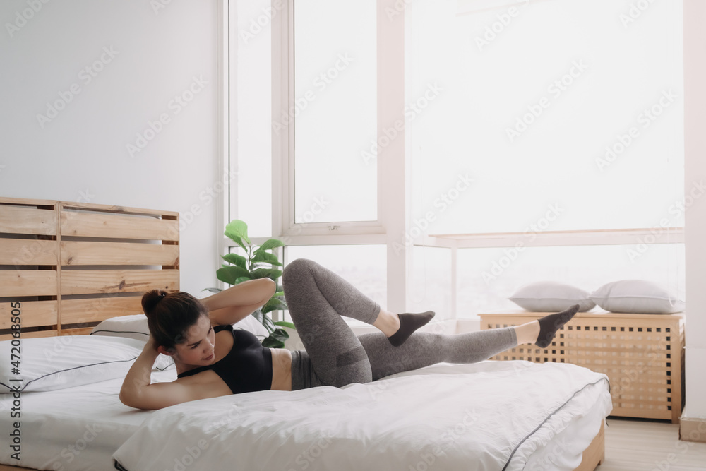 Asian woman do Cross Body Crunch exercise in her bedroom apartment. Asian woman do Cross Body Crunch exercise in her bedroom apartment.