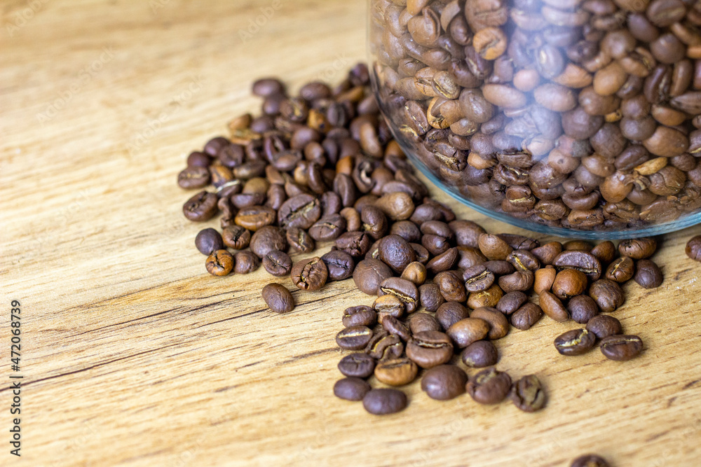 Roasted coffee beans in glass can on wooden table