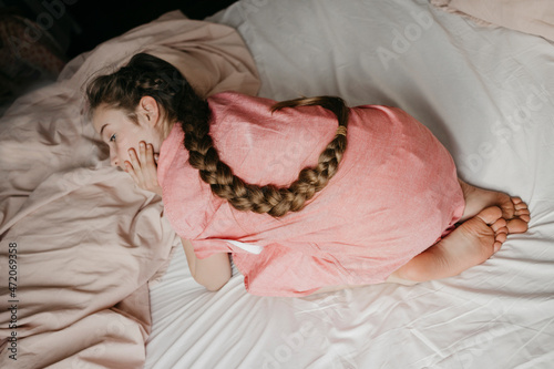 Girl with braided hair lying on bed at home photo