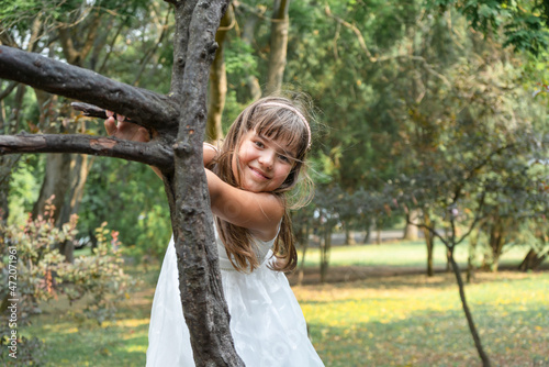 happy girl with long hair in a white dress among the trees in the park