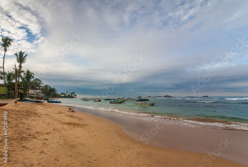 Summer landscape with sea  boats  sandy shore and sky with clouds on the coast of the Indian Ocean in Sri Lanka