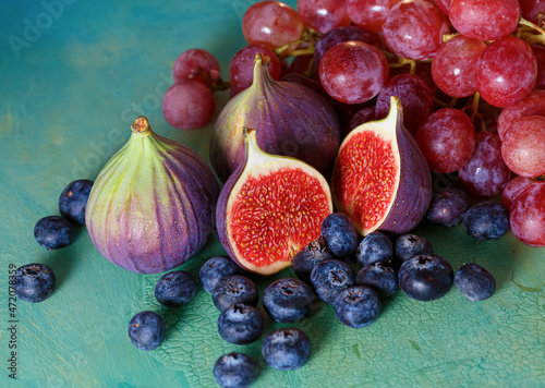 Top view of figs, pink grapes and blueberries on a green old table. Close-up.