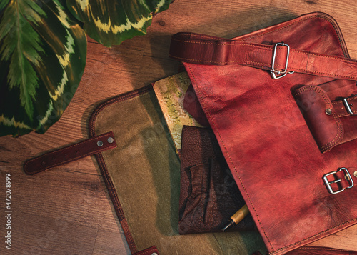 Overhead image of a leather messenger bag with a leather book and a notebook and pen