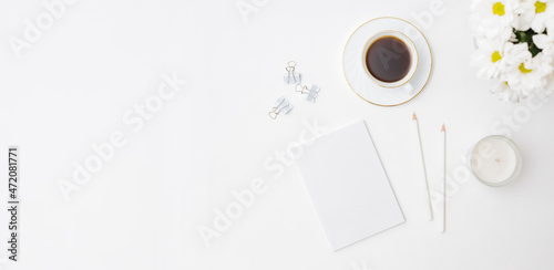Mockup white notebook, white flowers, a cup of coffee on a white background