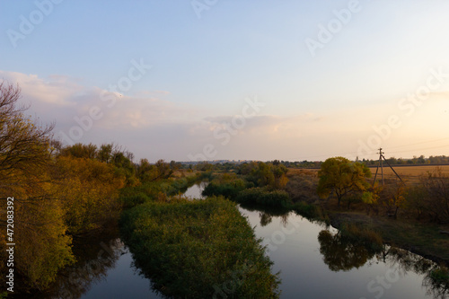 autumn landscape with a view of the river at sunset. Trees along the banks with colorful leaves
