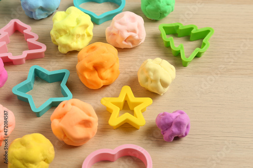 Different color play dough with molds on wooden table