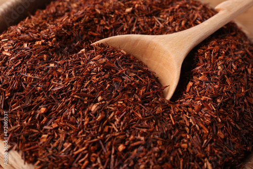 Spoon dry rooibos leaves in wooden bowl, closeup
