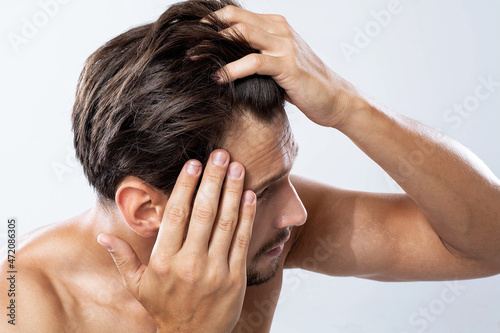 Man looking at his receding hairline