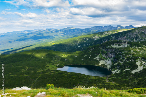 Fototapeta Naklejka Na Ścianę i Meble -  At the top of the high mountains you can see the blue sky, sunny clear weather, the mountains are covered with greenery and you can see the lakes from the melted snow. Unique nature and view