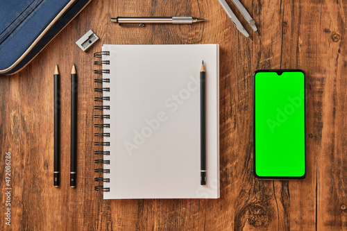 Concepto de dibujo y deseño con pantalla verde, lapices de trazado y cuaderno para bocetos sobre fondo de madera desde una vista cenital.  photo