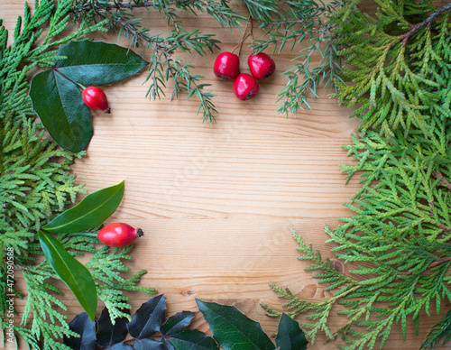 christmas card with fir branches, evergreens and berries. On a wooden background  
