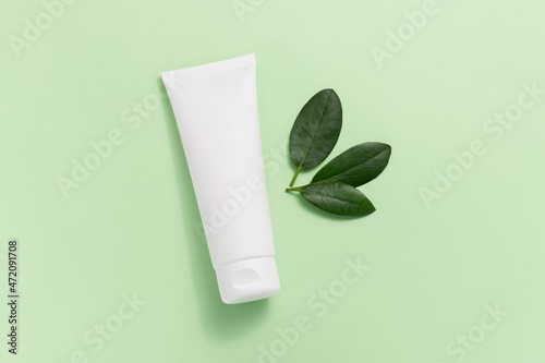 Wallpaper Mural Mockup white tube of face cream with green leaves top view, light green delicate background Torontodigital.ca