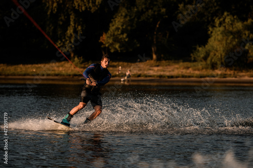 view of athletic man holding rope and riding on wakeboard