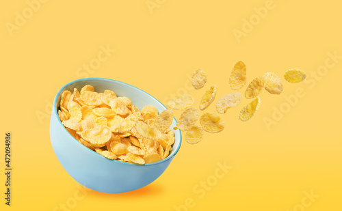 dry corn flakes in a blue ceramic plate, some of the corn flakes are flying in the air. traditional cornflakes breakfast concept