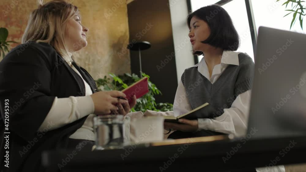 Closeup shot of two happy businesswoman talking about company strategy in office Closeup shot of two happy businesswoman talking about company strategy in office