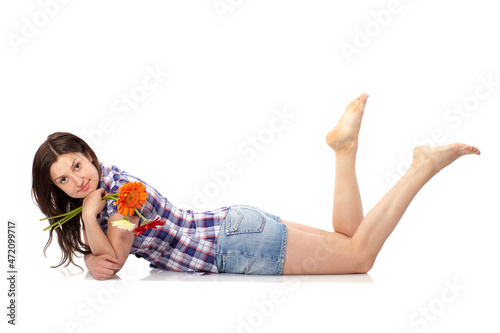 Beautiful young woman lying down on the floor with flowers isolated on white. Casual young relaxed and happy woman cut out in full length body.