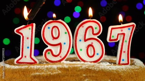 Birthday cake with white burning candles in the form of number 1967