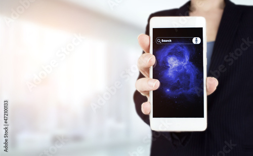 Hand hold white smartphone with digital hologram sign on light blurred background. Searching Internet Data. Web Browsing Concept. Searching information data on internet networking concept.