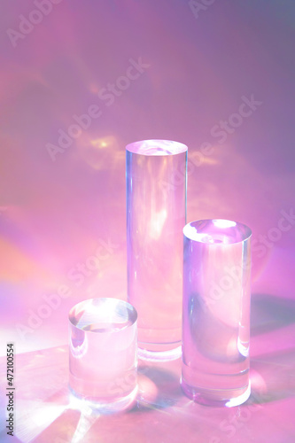 Abstract surreal scene - empty stage with three clear glass cylinder podiums on pastel pink holographic background in water. Pedestal for cosmetic product packaging mockups display presentation