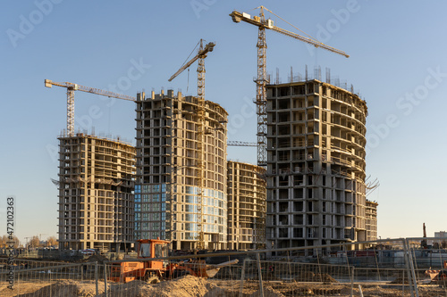 Photo of the construction site and building of high buildings and cranes against blue sky in the city. Constructional concept