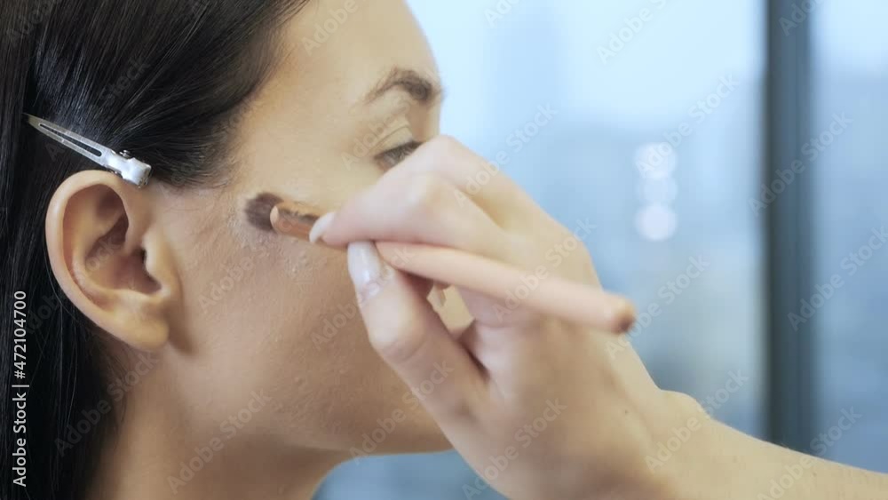 A professional make-up artist does makeup for a young girl. make-up artist corrects facial imperfections with foundation A professional make-up artist does makeup for a young girl. make-up artist corrects facial imperfections with foundation